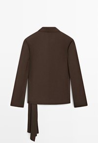 Donkerbruine blazer met lange mouwen, een kraag en een asymmetrische stoffen plooi die aan de linkerkant aan de achterkant hangt.