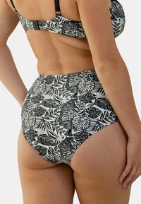 Bas de bikini taille haute en noir et blanc avec un motif de feuilles, doté d'un tissu lisse et d'une silhouette ajustée. Taille ajustable.