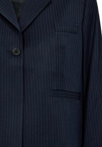 Marineblauwe pinstripe blazer van fijne stof, met een enkele knoop, notched revers en een borstzak aan de linkerkant.