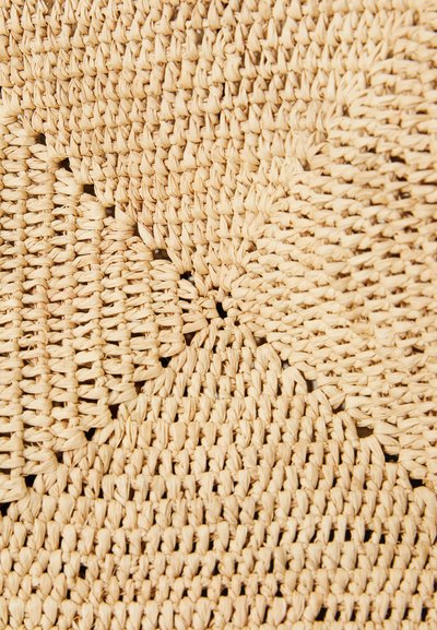 Tappeto intrecciato in paglia naturale con superficie texturizzata di un colore beige chiaro; presenta motivi intricati e stili di tessitura variabili.