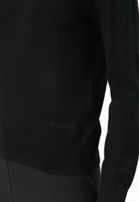 Black knit sweater featuring a fitted design with ribbed cuffs and hem. Subtle Calvin Klein logo near the bottom. Smooth texture.