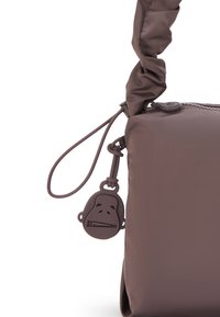 Brown nylon handbag featuring a textured surface, knotted strap, and a rubber monkey-shaped charm attached to the zipper pull.