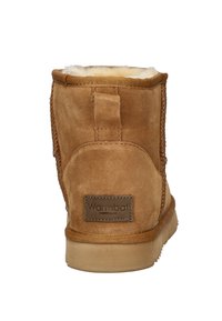 Bottine en cuir suédé marron avec une doublure douce en shearling blanc et une languette au talon. Présente des coutures décoratives et une étiquette de marque à l'arrière.