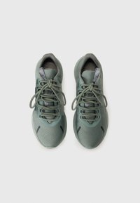Zapatillas deportivas verdes con un upper texturizado, cuello acolchado y cordones redondos. Presentan una forma elegante y sutiles acentos negros en los laterales.