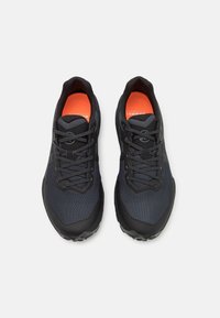 Baskets de sport noires avec un maillage texturé et des semelles en caoutchouc. Comprend des lacets gris et une semelle intérieure vibrante orange. Design léger et profil bas.