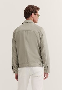 Light gray jacket featuring a simple design, smooth texture, and a straight fit. Includes a collar and subtle stitching details.