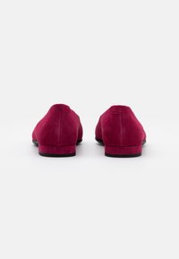 Burgundy suede loafers with a low black heel. Smooth texture and simple design, featuring a rounded toe and clean lines.