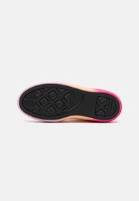 Black rubber sole of a sneaker with geometric tread pattern, gradient pink and orange midsole, shown against white background.