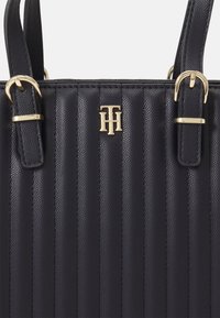 Himmelblaues, strukturiertes Lederhandtasche mit vertikalen Streifen, goldenen Hardware-Akzenten und hervorgehobenem, geprägt Logo auf der Vorderseite. Doppelte Griffe inklusive.