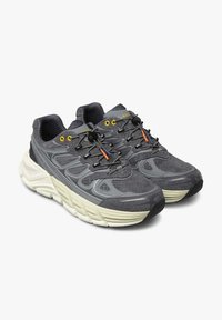 Scarpe da ginnastica grigie con una tomaia testurizzata, caratterizzate da vivaci accenti gialli e arancioni, una spessa intersuola bianca e un sistema di lacci sicuro.