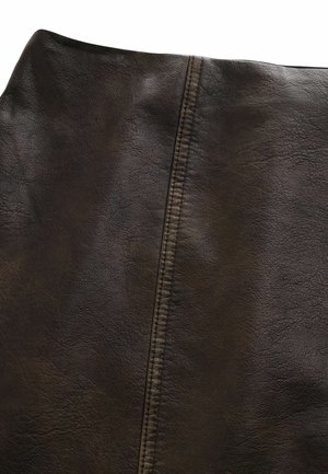 Artimųjų planas tamsiai rudos odos, matoma grūdinė tekstūra ir centrinė vertikali siūlė su dviguba siuvimo linija.