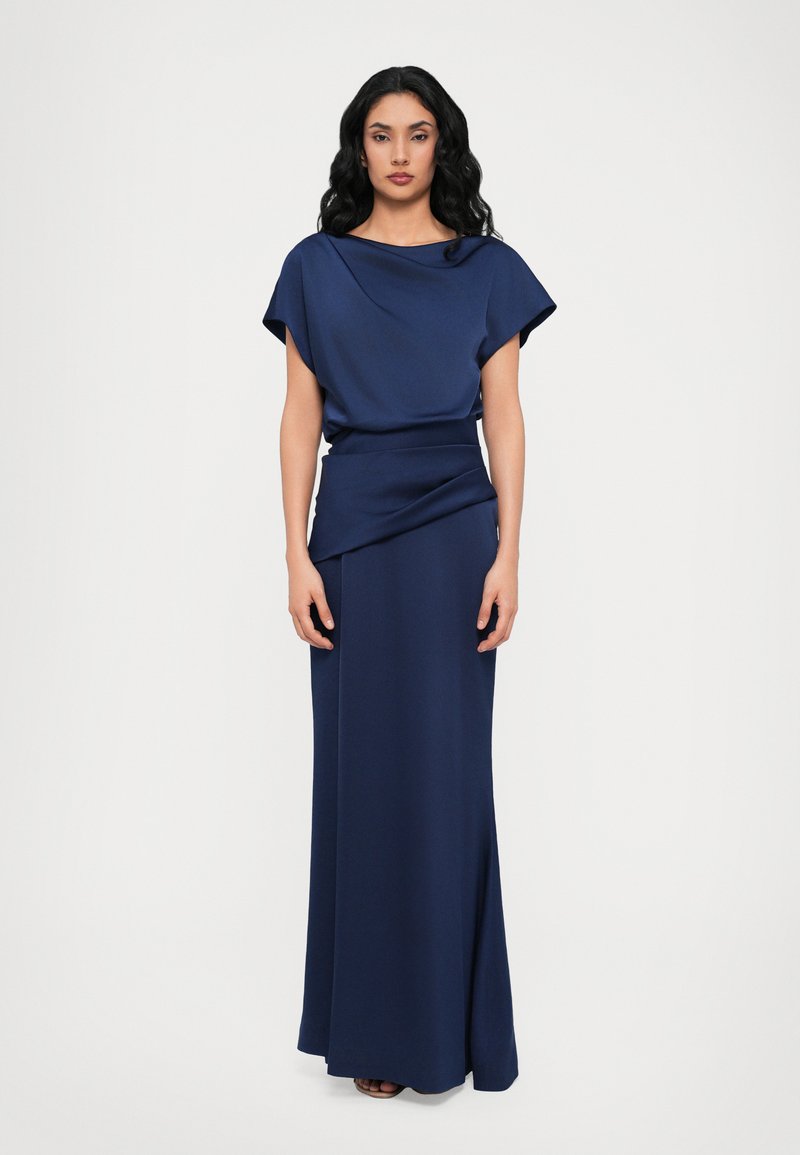 Long navy blue dress with a draped cowl neckline and short batwing sleeves. Smooth, matte texture and fitted waist, flows to a straight skirt.