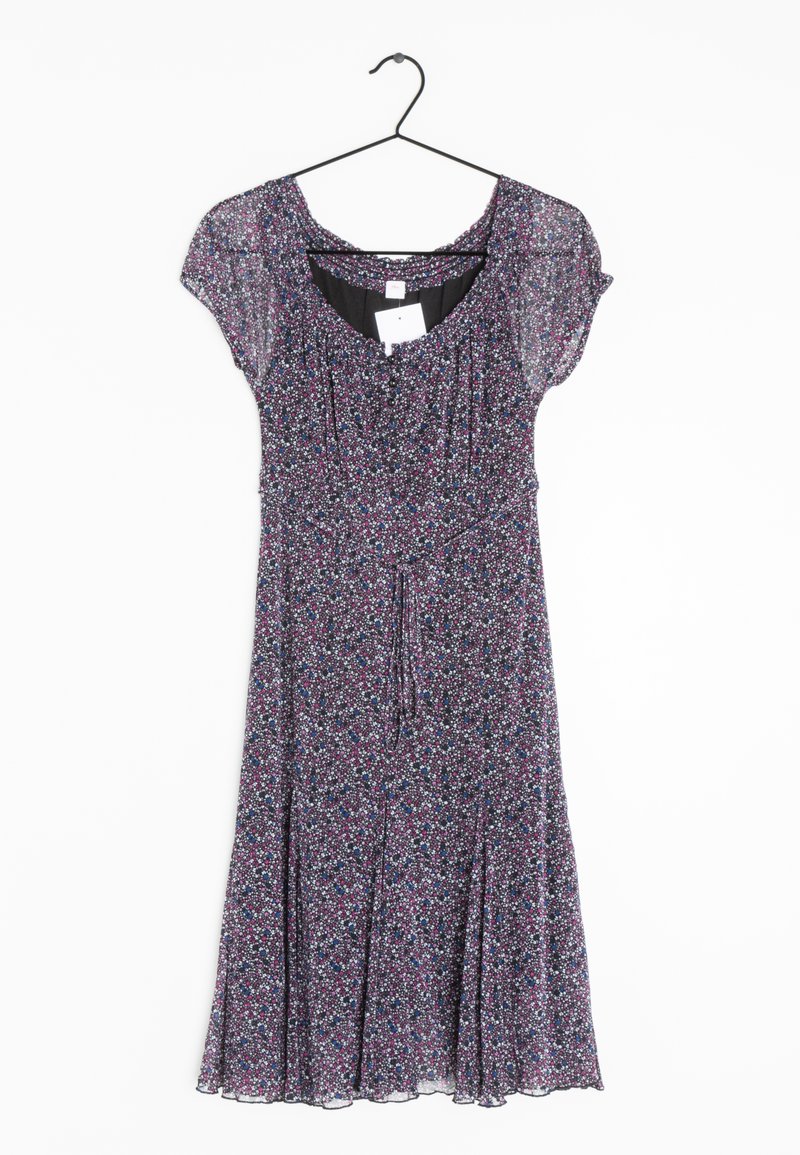 Robe midi à manches courtes avec petit motif floral violet, blanc et bleu, suspendue sur un cintre noir sur fond blanc.