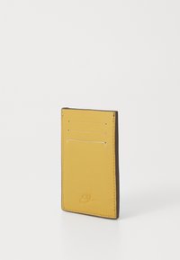 Yellow leather card holder with four vertical slots, brown edging, and embossed logo. Smooth texture with minimalistic design.