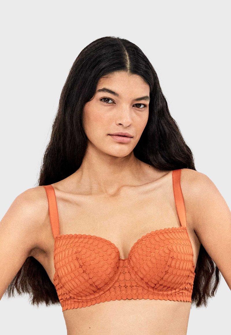 Soutien-gorge balconnet orange avec des détails texturés et festonnés, des bretelles ajustables, et une finition en tissu lisse. Conçu pour le soutien et le confort.