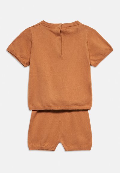 Καφέ πλεκτό τοπ με κοντά μανίκια και αντίστοιχα πλεκτά σορτς, τοποθετημένα επίπεδα, δείχνοντας την πίσω πλευρά και μια μικρή λεπτομέρεια με άνοιγμα κλειδιού στη γραμμή του λαιμού του τοπ.