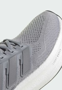 Lagani sivi atletski tenisice sa teksturiranom mrežastom gornjištu, sivim naglascima i bijelom "Light Boost" ublaženom potplatu.