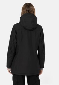 Svart vattentät parka med en huva, som har en strömlinjeformad design, långa ärmar och en längre bakre fåll. Slät textur, inga synliga mönster.