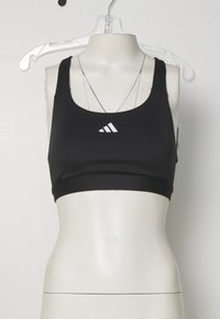 Svart trenings-BH med brede stropper, laget av elastisk materiale. Har en hvit Adidas-logo på forsiden og en glatt, tettsittende design.