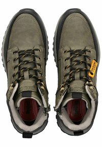 Botas de senderismo de cuero verde con detalles en negro, ojetes dorados y suelas texturizadas. Cuentan con soporte reforzado para el tobillo y cordones duraderos.