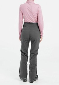 Grå skidbyxor med figursydd midja, dragkedjor vid anklarna och en mjuk textur, i kombination med en langärmad ljusrosa topp.