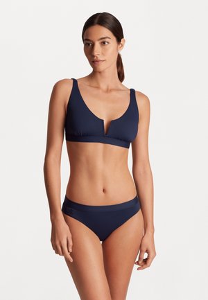 Námornícky modrý bikini set s trojuholníkovým braletom so širokými ramienkami a hlbokým V-výstrihom, doplnený stredne vysokými spodnými časťami, hladká textúra.