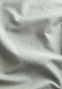 Hellgrauer Stoff mit einer glatten, leicht strukturierten Oberfläche, mit sanften Falten und subtilen Schattierungsvariationen.