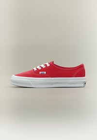 Κόκκινο παπούτσι Vans χαμηλού ύψους με λευκά κορδόνια, λευκή λαστιχένια σόλα και ορατό λογότυπο Vans στο πλάι και στη φτέρνα, απεικονισμένο σε προφίλ.