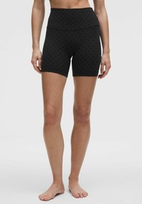 Sorte shorts med høj talje, prydet med prikket mønster. Fremstillet af et strækbart stof, de er designet til komfort og bevægelse.