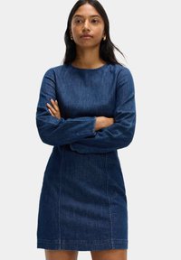 Denimklänning med rak silhuett, långa ärmar, rund halsringning, mörkblå färg och synliga sömnadsdetaljer.