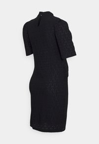 Zwarte kanten jurk met een gestructureerd ruitpatroon, korte mouwen en een sleutelgaatje aan de achterkant met een knoopdetail. Strak aansluitende silhouet.