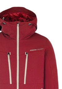 Rode geïsoleerde jas met een hoge kraag, witte ritsen, geperforeerde details en een logo op de borst. Geverfde stoftextuur en sportief ontwerp.