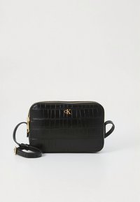 Juoda stačiakampė rankinė per petį su krokodilo odos raštu, auksiniu užtrauktuku, reguliuojamu diržu ir mažu auksiniu „cK“ logotipu priekyje.