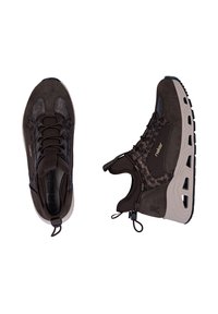Paire de chaussures de sport marron foncé avec dessus texturé, épaisses semelles beiges à motifs découpés et tirettes, sur fond blanc.