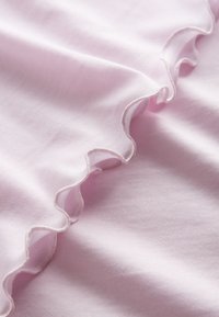 Light pink fabric featuring a ruffled edge, smooth texture with a slight sheen, and a cozy, stretchable design.