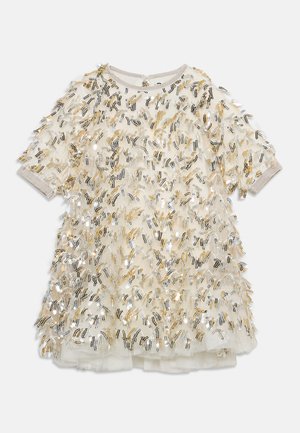 Robe courte couleur crème avec tulle en couches et embellissements en sequins dorés, argentés et noirs sur toute la surface.