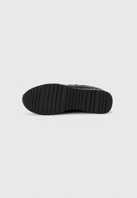 Black sneaker sole with a textured, ridged surface; made of rubber material; features a flat design for grip and stability.