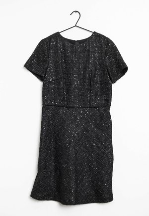 Vestido negro de manga corta con textura de lentejuelas, colgado en una percha negra contra un fondo blanco.