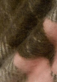 Tissu en laine tricotée dans des tons terreux de brun et de rose, présentant un motif texturé avec des fibres douces et bouclées ainsi qu'une surface lisse semblable à du feutre.