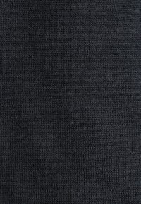 Gros plan sur un tissu tricoté gris foncé montrant des points fins et réguliers ainsi qu'une texture lisse et homogène.