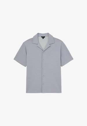 Chemise à manches courtes gris clair texturée avec col de style camp et cinq boutons sur le devant, posée à plat sur un fond blanc.