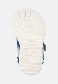 Kenkän pohja, jossa on valkoinen kumipinta, vaakasaumot ja pyöristetyt reunat. Sisältää sinisiä ja harmaita kangasosia, joissa on merkintä "Camper 21."