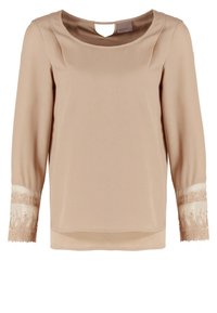 Blouse beige à manches longues avec encolure ronde et poignets en dentelle transparente ornés de broderies florales.