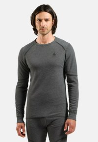 Chemise grise à manches longues avec un motif texturé, col rond et coupe slim. Présente un logo sur la partie supérieure gauche de la poitrine.