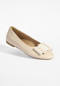 Ballerines beiges en cuir lisse, avec un accent de nœud texturé blanc sur le bout et une semelle discrète.
