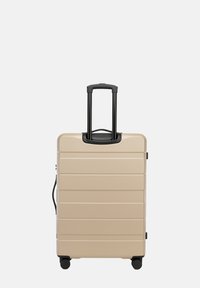 Tvrdý kufr v béžové barvě s texturovanými pruhy, vysouvací černá rukojeť a čtyři černá kolečka pro snadnou přenositelnost. Kompaktní a odolný design.
