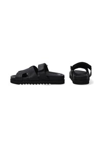 Sorte lædersandaler med udskæringsdesign, Velcro-strop, struktureret sål og en glat fodseng. Har en buet hæl for støtte.