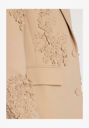 Beige op maat gemaakte blazer met bloemen applicaties op de mouwen en voorkant, gestructureerde vorm, met een enkele knoopsluiting en een opgestikte zak.