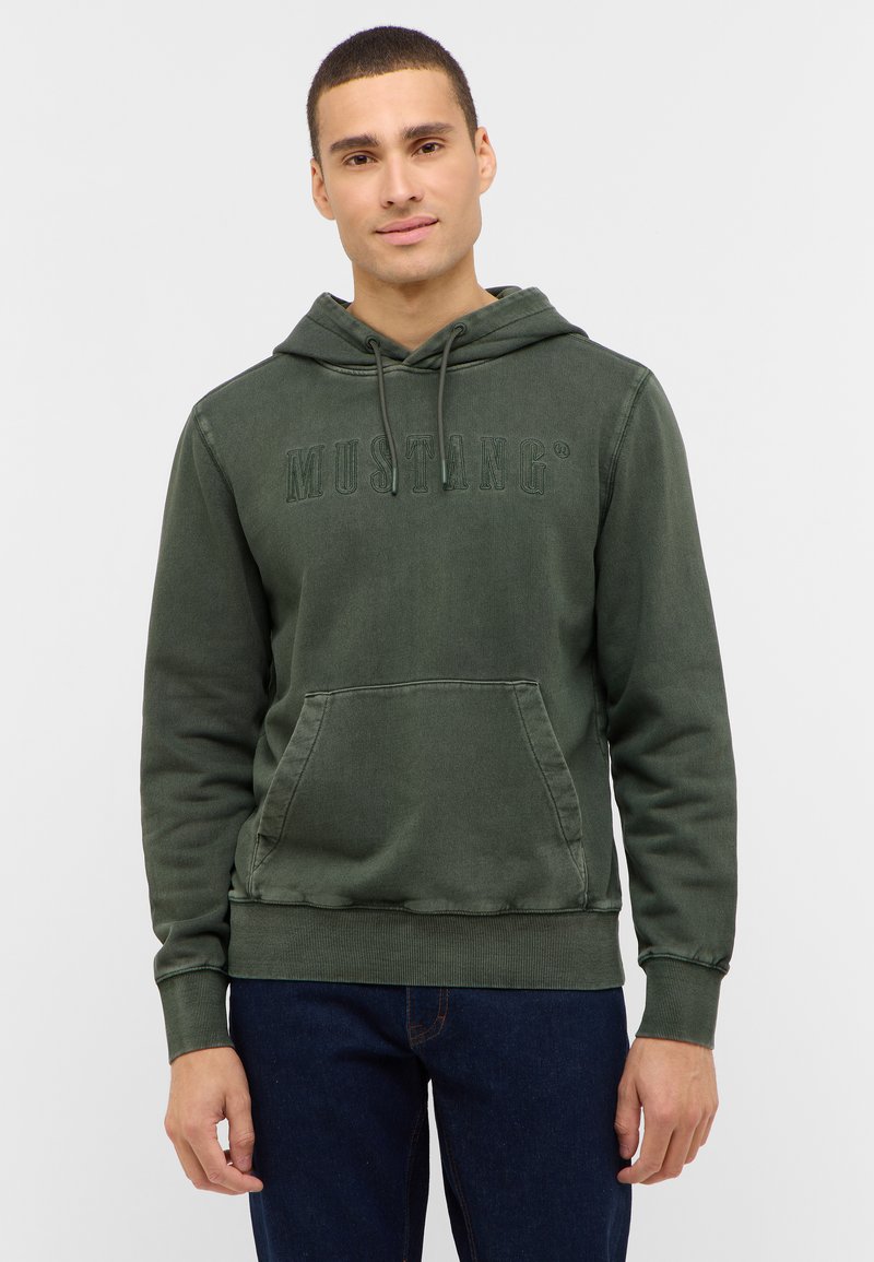 Khaki zelená mikina s kapucňou, predné vrecko, nastaviteľná šnúrka na kapucni a vystupujúce logo „MUSTANG“. Rebrované manžety a lem, voľný strih.