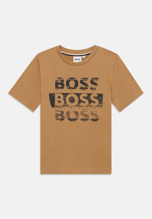 T-shirt beige à manches courtes avec trois impressions de texte "BOSS" usées en noir, dont une mise en évidence par un fond rectangulaire noir.
